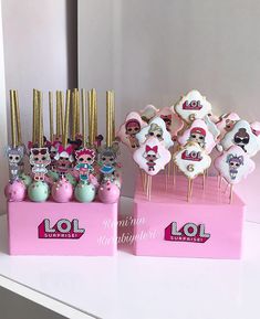 there are many decorated cookies on display in the pink boxes with gold sticks sticking out of them