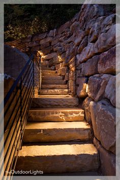 some stairs are lit up by lights in the dark, with rocks on either side