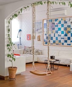 a living room filled with furniture and a wooden swing chair next to a white couch