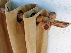 a pair of brown boots hanging from a hook on a white wall next to a piece of wood