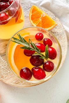 a glass bowl filled with orange juice and cherries