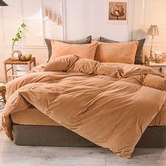 a bed with brown sheets and pillows in a room next to a lamp on a table