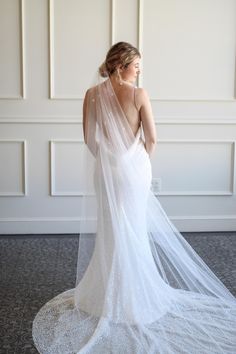 a woman in a wedding dress with a veil on her head is looking back at the camera