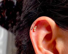 an ear piercing with three small flowers on the top of it's middle ear