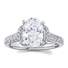 an oval cut engagement ring with pave set diamonds on the shoulders and sides, in 18k white gold