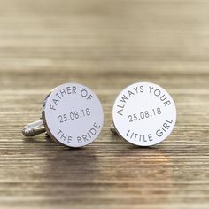 two silver cufflinks with graduation caps on them sitting on a wooden table top