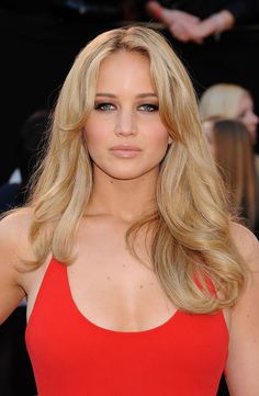 a woman with long blonde hair wearing a red dress and posing for the camera at an event