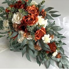 an orange and white bridal bouquet with greenery