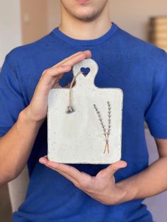 a man holding a ceramic cutting board with two flowers on it's front and back