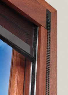 a close up of a window with a metal curtain on it's side and a blue sky in the background