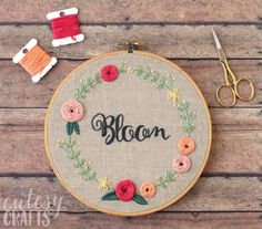 an embroidered hoop with the word mom on it next to some scissors and other crafting supplies