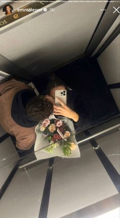 a man taking a selfie with his cell phone in front of him and flowers on the floor