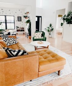 a living room filled with lots of furniture and plants on top of the tables in front of them