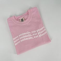 "This comfy vegan activism t-shirt features our \"Love Animals, Eat Plants\" graphic on the front and is blank on the back. Material: 100% ringspun cotton that is preshrunk, soft-washed, and made from garment-dyed fabric. Fit: Unisex. Make sure to check the size chart (swipe through photos). Care: Wash inside out and tumble dry low or hang dry. Do not iron or dry clean." Vegan Tote Bag, Vegan Gifts, Animal Rights, Canvas Bag, Size Chart, Crew Neck Sweatshirt, Tops & Tees, Adult Outfits, Top Outfits