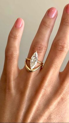 a woman's hand wearing a gold ring with a pear shaped diamond on it