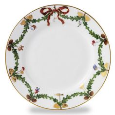 a white and gold plate with holly wreaths on the rim, decorated with red bows