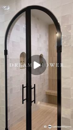 a walk in shower sitting next to a white tiled wall with black trim and an arched glass door