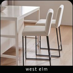 two white chairs sitting next to each other on top of a hard wood floored floor