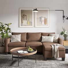 a living room with a sectional couch and two pictures on the wall above it, along with a coffee table