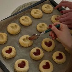 someone is making heart shaped cookies on a baking sheet