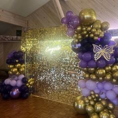 purple and gold balloons are on display in front of a mirrored wall with butterfly decorations