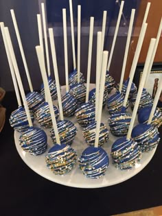 blue and gold cake pops on a plate with white sticks sticking out of the top