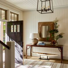 an entryway with a table, mirror and lamp