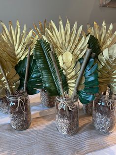 four mason jars with plants in them sitting on a table