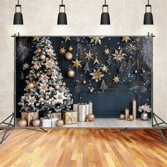 a christmas tree and presents in front of a backdrop with gold snowflakes on it