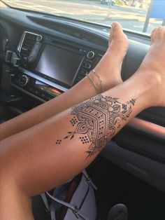 a woman's legs with tattoos on the inside of her car steering wheel and dashboard