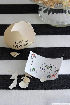 an egg shell and paper on a striped tablecloth with other eggs in the background