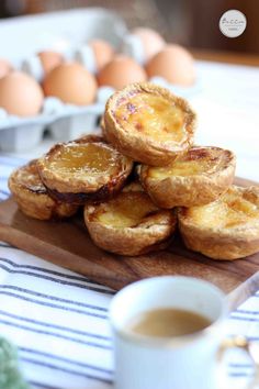 there are many small pies on the wooden board next to a cup of coffee