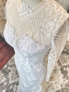 a mannequin wearing a white dress with intricate lace on it's shoulders