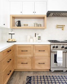 a kitchen with wooden cabinets and an oven in the center, along with a rug on the floor