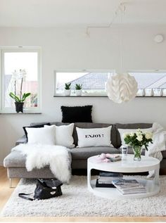 a living room filled with lots of furniture and white rugs on top of a hard wood floor