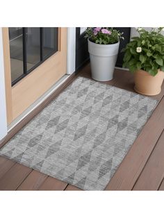 a door mat sitting on top of a wooden floor next to a potted plant