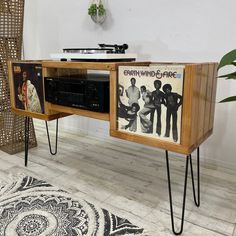 an old record player is sitting on some hairpin legs in front of a wooden entertainment center