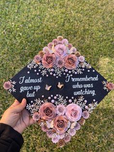 someone is holding up a graduation cap with flowers on it