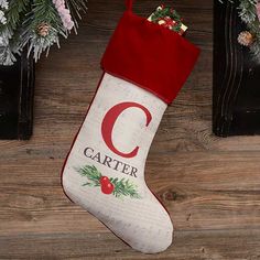 a christmas stocking with the letter c hanging from it's side on a wooden floor