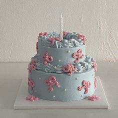 a three tiered cake with pink and blue icing on the top is sitting on a white surface