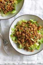 two plates filled with lettuce and meat on top of a white table cloth