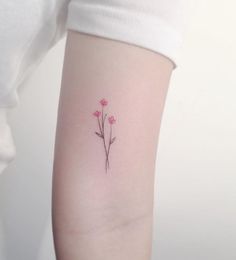 a small pink flower tattoo on the left arm