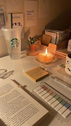 there is a candle on the table next to some books and papers with starbucks logos