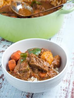 a white bowl filled with stew next to a green casserole dish