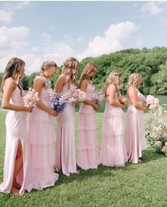 a group of women standing next to each other on top of a lush green field