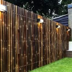 a wooden fence with lights on it in front of a house and grass yard area