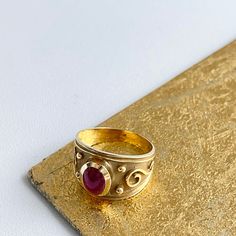 Estate/ vintage 14KT yellow Gold Byzantine/ Etruscan design polished + textured matte finish cigar band ring with genuine ruby. Elegant, old world piece with faceted, oval-shaped, cabochon, genuine red ruby. Ruby measures: 8mm x 5.7mm Size 7 Can be sized by your local jeweler or ours for a fee Solid Measures: 13.6mm wide~ graduated back to 3.5mm Weight: 4.6 grams Excellent condition Gold Ruby Ring With Domed Shape, Gold Domed Ruby Ring With Gemstone, Elegant Red Intaglio Signet Ring, Domed Ruby Gemstone Jewelry, Heirloom Ruby Signet Ring With Hallmark, Gold Ruby Ring With Bezel Setting, Oval Cabochon, Classic Oval Engraved Ruby Ring, Antique Hallmarked Ruby Signet Ring, Classic Gold Ruby Signet Ring