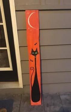 an orange painted sign with a black cat on it's face and the moon in the background