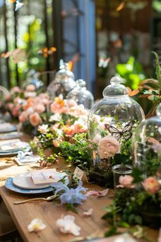 the table is set with flowers and glass cloches for an elegant wedding reception