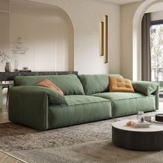 a green couch sitting on top of a wooden floor next to a table and window